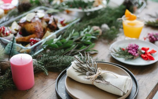 Featured image for the article "Creating the Perfect Winter Wonderland Soiree: A Comprehensive Guide to Throw Unforgettable Indoor Party in 2024". showing High angle of table served for Christmas dinner with plates with napkins and traditional roasted turkey on glass dish decorated with fir twigs