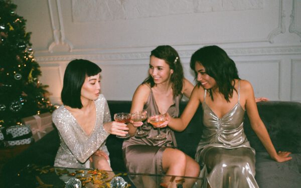 Featured image for the article "Mardi Gras 2024: How to Plan an Epic New Orleans-Style House Party". showing Three Women Sitting on a Sofa