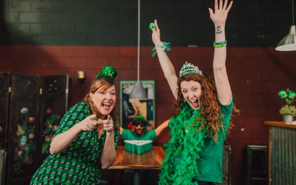 Featured image for the article "Mastering the Art of Hosting: Preparing for an Unforgettable St. Patrick’s Day Party in 2024". showing Women in Green Outfits Celebrating St Patrick's Day