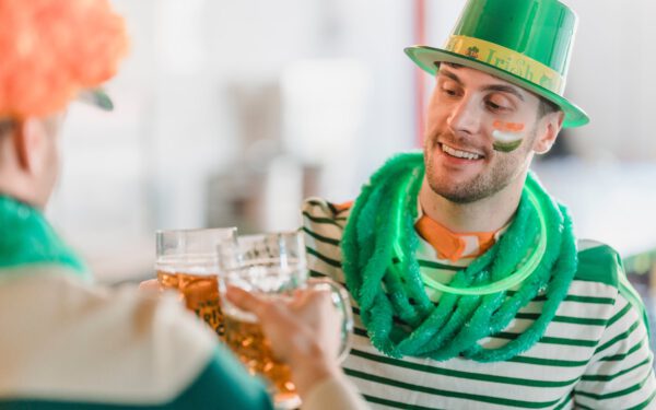 Featured image for the article "St. Patrick’s Day 2024: Perfect Playlist and Games to Uplift Your Irish Themed Party". showing Cheerful friends clinking glasses of beer on St Patricks day