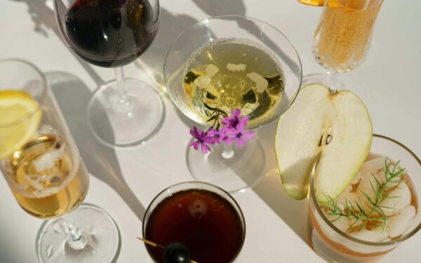 Featured image for the article "Easter Extravaganza 2024: Innovative Drink Recipes and Party Games to Celebrate the Day in Style". showing Glasses of cocktails decorated with pear and blooming flowers