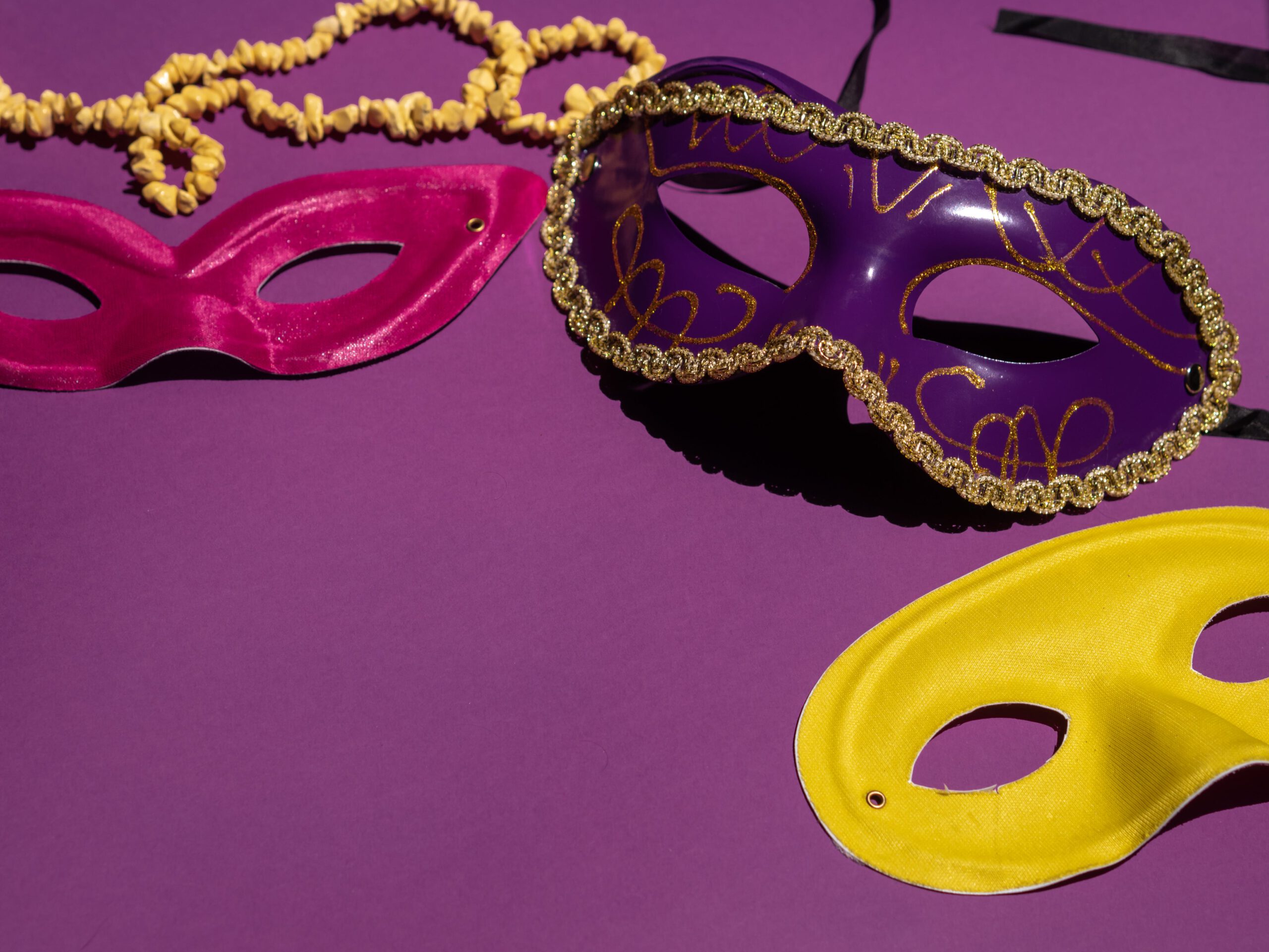 Illustration of Different Colored Masks on a Purple Surface for the article titled The Ultimate Guide to Throwing an Electrifying Mardi Gras Party 2024: Decoration, Costume and Entertainment Ideas photographed by Polina Kovaleva