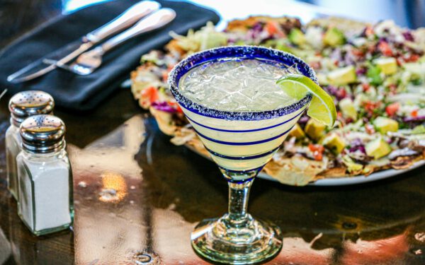 Featured image for the article "Cinco De Mayo Fiesta 2024: How To Plan The Ultimate House Party With Authentic Mexican Cocktails And Games". showing Margarita Glass on Table