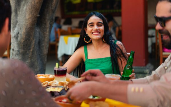 Featured image for the article "Secrets to Hosting an Eclectic Cinco de Mayo Fiesta 2024: A Comprehensive Guide to Drink Games, Food and Music". showing Woman in Green Tank Top Smiling